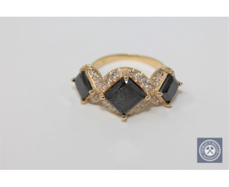 A 14ct yellow gold trilogy halo black and white diamond ring featuring 3 black diamonds 4.45ct and 48 white round brilliant c