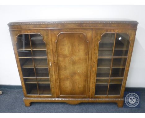 An early 20th century walnut triple door display cabinet on bracket feet