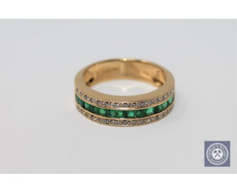 An 18ct gold emerald and diamond half-eternity ring, size N