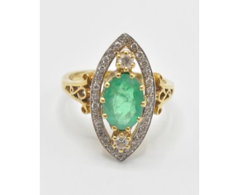 A hallmarked 18ct gold emerald and diamond ring. The ring having a pierced marquise shaped head set with a central oval cut e