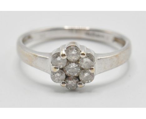 A vintage 20th Century white gold and diamond cluster ring having a flower head set with seven round cut diamonds. Band marke