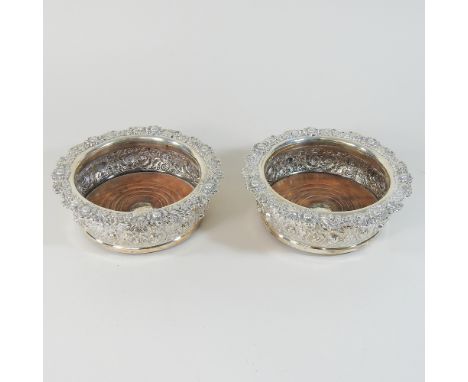 A pair of William IV silver wine coasters, each of circular shape, decorated in relief with a continuous row of flowers and f