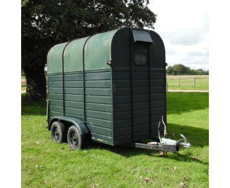 A green light weight pony trailer, with a metal floor and twin axle, bearing a label for J &amp; B Towing, 405cm long overall