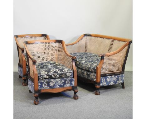 A 1920's single cane walnut bergere suite, to include a sofa, 172cm and two chairs, on claw and ball feet