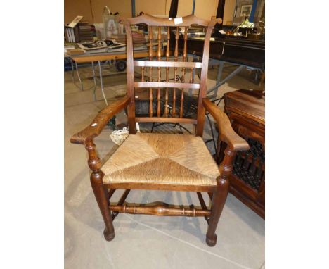 An ash rush seated Ladder back carver chair with turned stretchers and pad feet