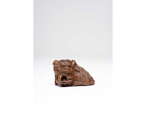 A JAPANESE BOXWOOD NETSUKE OF A SHISHIMEIJI ERA, 19TH CENTURYSeated on its haunches and resting its head on a reticulated bal
