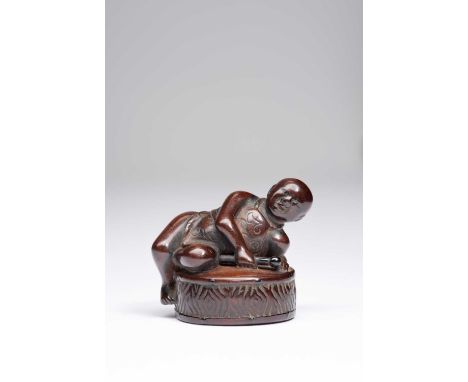 A JAPANESE WOOD NETSUKE EDO OR MEIJI, 19TH CENTURYModelled as a boy resting on a large drum, the child depicted wearing a sim