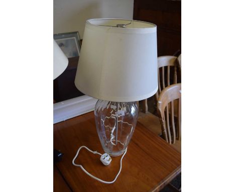 A modern table lamp with clear glass vase formed base