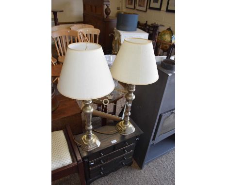 A pair of heavy cast metal candlestick type table lamps with cream shades
