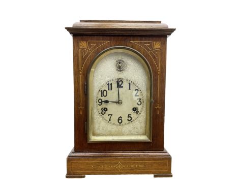 Edwardian - 8-day mantel clock in a mahogany case with satin wood inlay, flat toped case with an arched glazed door, silvered