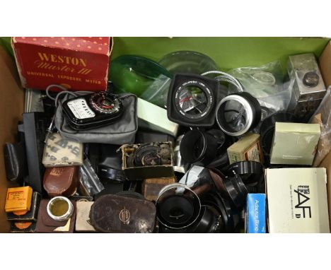 A box of miscellaneous camera items, including portable dark slide developing tin, Western light meters, a boxed Nikon AF Zoo