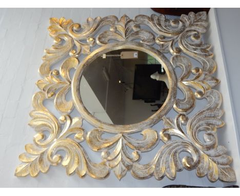 A carved wood and gilt wall mirror, the circular plate within pierced foliate decoration. W. 120cm