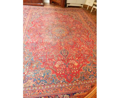 A red ground Tabriz carpet, decorated with teardrop medallion to centre within foliate design, fringed, L. 372cm, W. 286cm