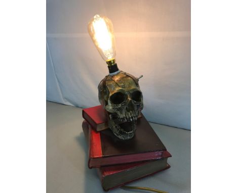 Reproduction skull lamp situated on a stack of 3 three books. working order 
