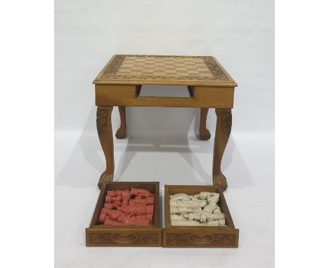 Carved wooden chess table&nbsp;with carved decoration, drawers on either side containing resin chessmen in white and red, 39c