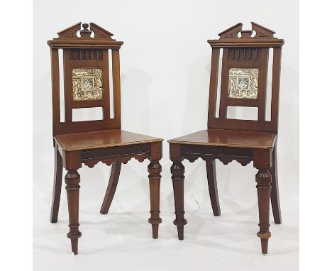 Pair of 19th century mahogany hall chairs with broken arch top rails, the back splats featuring tile, with central rams head 