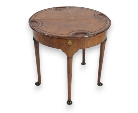 A George III mahogany triple top tea and games table of demi-lune form, the gaming top with leather skiver and counter wells 