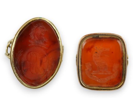 Two Victorian yellow metal and agate set intaglio rings, both matrix carved with a crest, one with monogram also, sizes K and