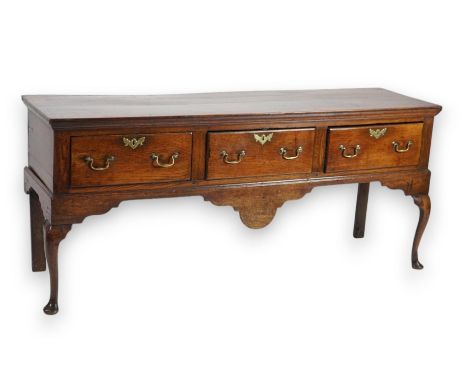 A George III oak dresser base with three long drawers and shaped apron, on cabriole legs with pad feet, 183cm wide, 50cm deep