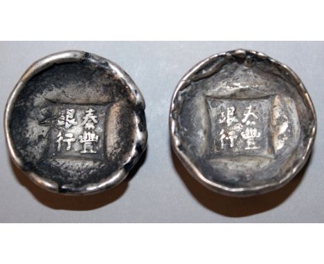 TWO CHINESE SILVER-METAL INGOTS, weighing approx. 60gms each, each with impressed character marks, each 1.3in diameter. (2)