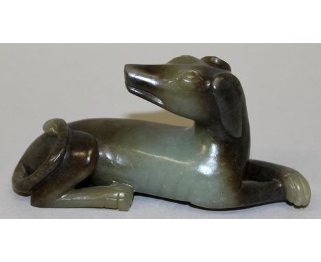 AN UNUSUAL CHINESE JADE MODEL OF A HOUND, lying with front paws crossed and its head turned back along its body, the stone of