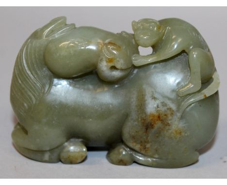 AN EARLY 20TH CENTURY CHINESE DARK CELADON GREEN JADE MODEL OF A KNEELING HORSE, its head turned backwards to face a monkey c