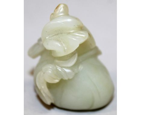 A SMALL CHINESE CELADON JADE MODEL OF A FRUIT, decorated in relief with a small bird perched on a branch, 1.6in high.