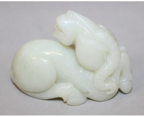 A CHINESE WHITE JADE MODEL OF A RAM, seated with head turned backwards, 2.1in long.