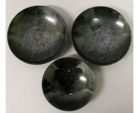 A GROUP OF THREE EARLY 20TH CENTURY CHINESE DARK GREEN JADE-LIKE SAUCER DISHES, the largest 4.7in diameter. (3)