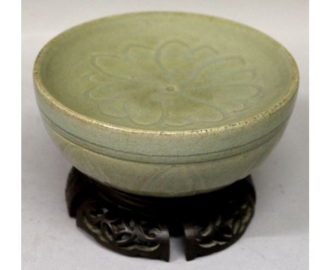 AN UNUSUAL CHINESE MING STYLE CELADON CERAMIC BOWL, together with a pierced and carved fitted wood stand, the shallow interio