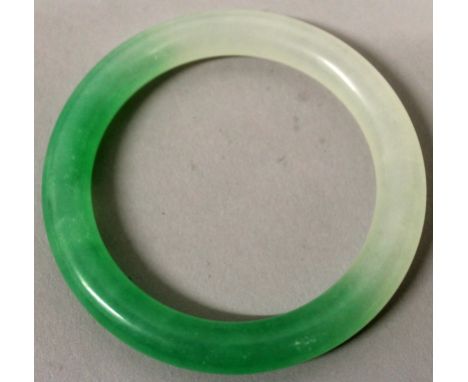 A CHINESE JADE BANGLE, the stone of white and of apple-green hue, 3in diameter, the inner rim 2.2in diameter.