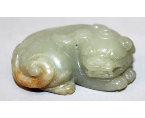 A CHINESE JADE-LIKE MODEL OF A BUDDHISTIC LION, lying down with its head turned and resting on its paws, the predominantly ce