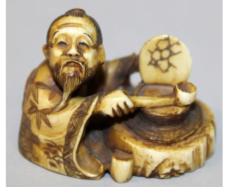 A SIGNED JAPANESE MEIJI PERIOD STAINED IVORY NETSUKE, of a man kneeling before a cauldron with a ladle in his hand, the base 