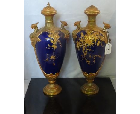 A pair of late Victorian Royal Worcester oviform vases with covers, having gilded flowers on a cobalt blue ground with green 