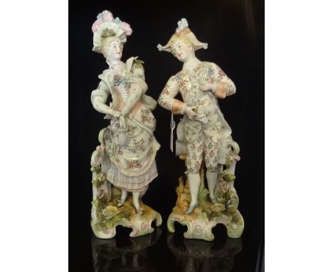 A pair of large 19th century Continental ceramic figurines, a dandy in tricorn hat and a finely dressed lady, each on florall