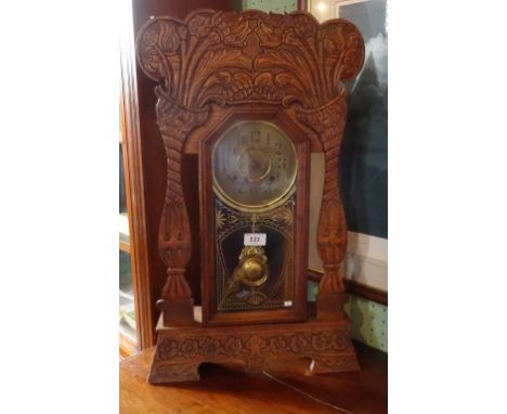 A floor standing oak cased American clock, having carved floral decoration, the brass dial bearing Arabic numerals, label ver