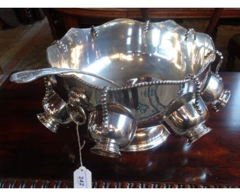 A large silver plated punch bowl on pedestal foot, with eight cups and serving ladle, 31cm diameter.