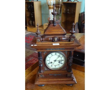 A late Victorian oak mantle clock, surmounted by stepped and turreted decoration, the enamel dial bearing Roman numerals, the