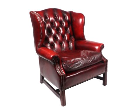 A George III style oxblood leather button back wing armchair on tapering square legs joined by a stretcher.Condition ReportSt