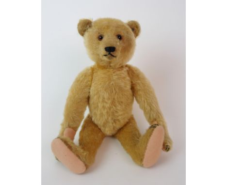 A 1920's Steiff teddy bear with glass eyes and ear button, 33cm high (some wear and bare patches on head and right arm)