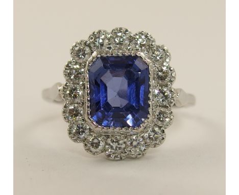 An 18ct white gold blue gem stone and diamond ring the cornflower blue gem stone is emerald cut and milligrain set surrounded