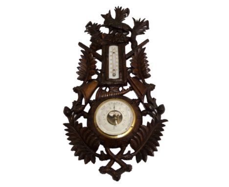 A black forest stained barometer and thermometer carved with sporting trophies, fox and foliage, 63cm high