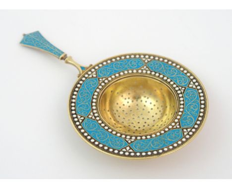 A Scandinavian silver gilt and enamel tea strainer marked 925, the circular pierced bowl with blue enamel decoration enclosed