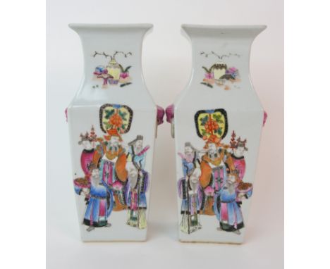 A pair of Canton famille rose square baluster vases painted with mandarins and courtesans divided by calligraphy beneath fixe