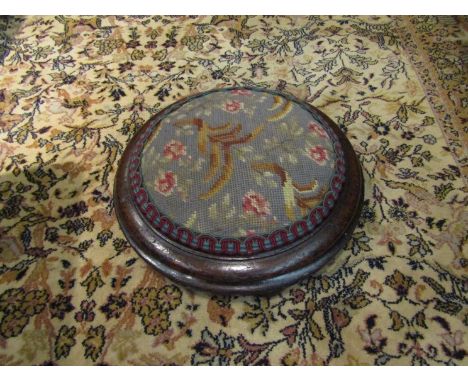 A circa 1840 mahogany circular footstool with tapestry upholstery over bun feet, 35cm diameter