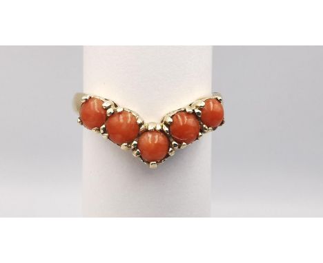 A 9ct yellow gold coral V-shaped ring. Set with five round red coral cabochons in open back claw settings with a combined app