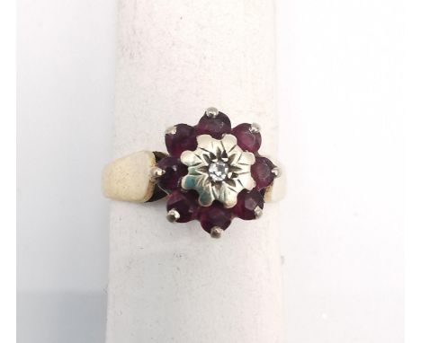 A pink metal (tests as 9ct) ruby and diamond cluster ring. Ring set to centre with a round eight cut diamond with an approxim