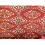 A handmade Pakistan rug, medallions on a rust coloured ground, cream and blue with a Turkish kelim