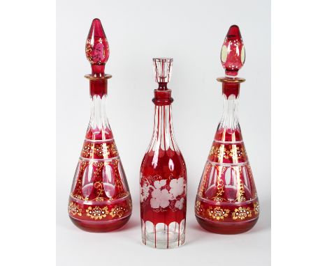 A PAIR OF BOHEMIAN RUBY TAPERING DECANTERS AND STOPPERS and another engraved with fruiting vines (3).