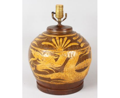 A LARGE BROWN POTTERY BULBOUS LAMP decorated with sea serpents. 9ins x 9ins, on a wooden base.